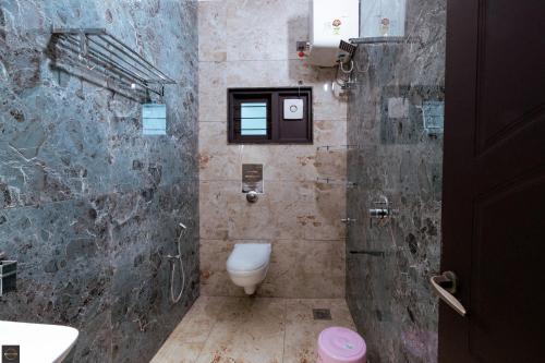 a bathroom with a toilet and a glass shower at Reunion Marina Villa in Udupi