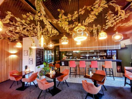 un restaurante con mesas y sillas naranjas y un bar en Hôtel L'Amandier en Libramont