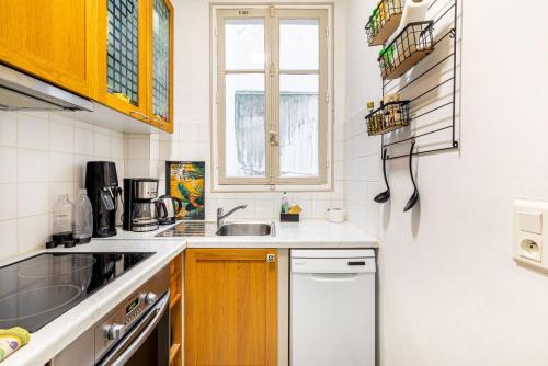 une petite cuisine avec un évier et une fenêtre dans l'établissement GuestReady - Bel Apt charmant près de Montmartre, à Paris
