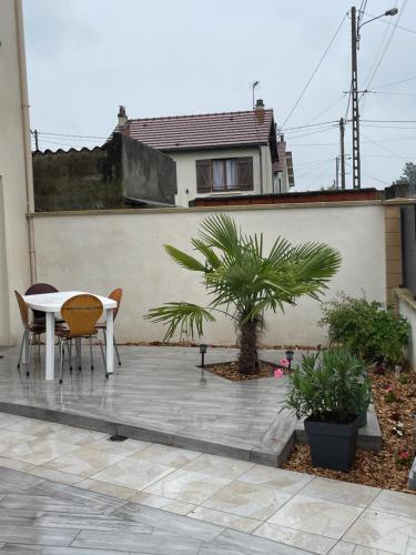 Un patio con mesa y sillas y una casa. en Maison JO 2024, en Villepinte