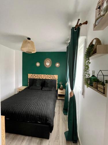 une chambre avec un lit noir avec un mur vert dans l'établissement Maison JO 2024, à Villepinte