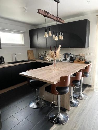 Una cocina con una mesa de madera y algunas sillas. en Maison JO 2024, en Villepinte