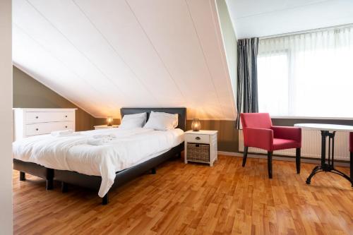 een slaapkamer met een bed en een rode stoel bij Hello Zeeland - Essenhoeve 2 Rosa Rugosa in Cadzand