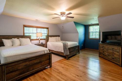 a bedroom with two beds and a flat screen tv at Lakefront Point Retreat on Nantahala Lake with Dock in Topton