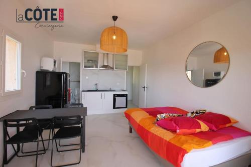 une chambre avec un lit, une table et un miroir dans l'établissement Le Phare, à Carry-le-Rouet