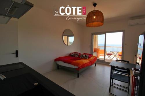 une chambre avec un lit avec une table et un miroir dans l'établissement Le Phare, à Carry-le-Rouet