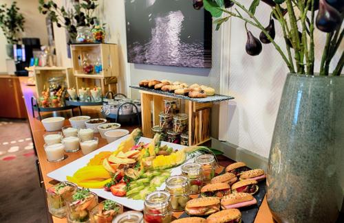 a table topped with sandwiches and vegetables and food at Leonardo Hotel Hamburg City Nord in Hamburg
