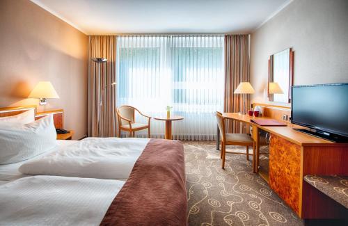 a hotel room with a bed and a desk and a television at Leonardo Hotel Hamburg City Nord in Hamburg