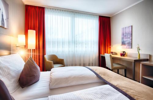 a hotel room with a bed and a desk and a window at Leonardo Hotel Hamburg City Nord in Hamburg