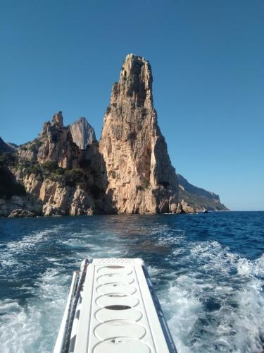 a boat in the water with a mountain in the background at Casa di Anna in Baunei