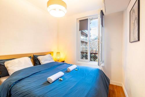une chambre avec un lit bleu avec une fenêtre dans l'établissement GuestReady - Serene Comfort near Sacré-Cœur, à Paris