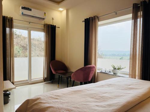 a bedroom with a bed and two chairs and a window at Rootz in Dehradun