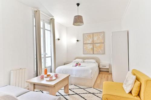 Cette chambre blanche dispose d'un lit et d'un canapé. dans l'établissement Studio paisible Parc des Buttes-Chaumont, à Paris