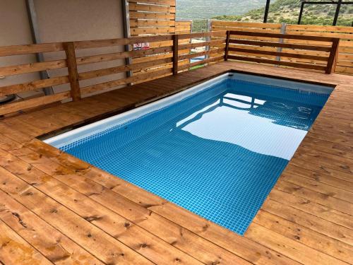 a swimming pool on a deck with a wooden fence at נגיעות בטבע - צימרים כפריים מקסימים כולל ארוחת בוקר ובריכה מחוממת in Bet Dagan