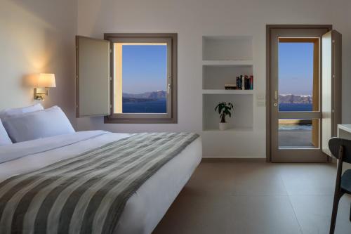 a bedroom with a large bed and two windows at Kalestesia Suites in Akrotiri