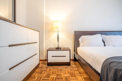ein Schlafzimmer mit einem Bett und einem Nachttisch mit einer Lampe in der Unterkunft GuestReady - Tranquil retreat in Lisbon in Lissabon