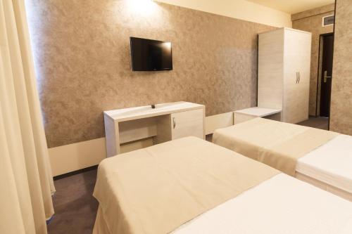 a room with two beds and a tv on the wall at YMY HOTELS Târgu Jiu in Târgu Jiu