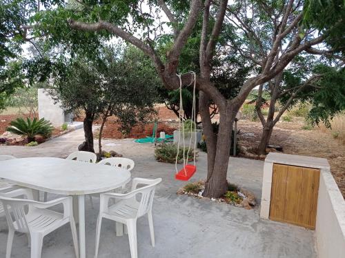 a white table and chairs and a swing under a tree at Villa Angelica in Capilungo
