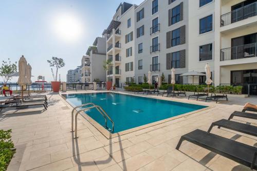 a swimming pool with benches and a building at GuestReady - Stylish blue elegance in La Cote in Dubai