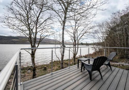 two chairs and a table on a deck overlooking a lake at Alba Pod in Fort Augustus