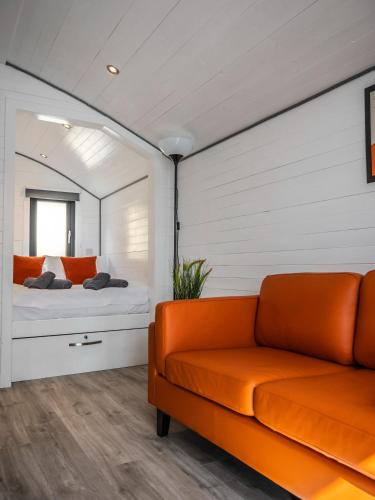 an orange couch in a bedroom with a mirror at Alba Pod in Fort Augustus
