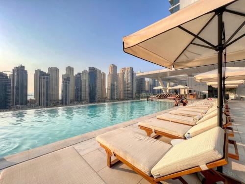 a pool with lounge chairs on the roof of a building at GuestReady - Opulent Residence in Dubai Marina in Dubai