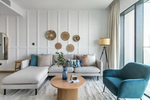 uma sala de estar com um sofá e duas cadeiras e uma mesa em GuestReady - Vida High-Floor Elegance em Dubai