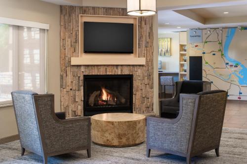 vestíbulo con chimenea, 2 sillas y TV en TownePlace Suites Richland Columbia Point, en Richland