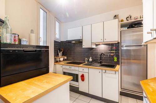 une cuisine avec des armoires blanches et un réfrigérateur noir dans l'établissement GuestReady - Apt. de charme pour 2 dans le 13e, à Paris