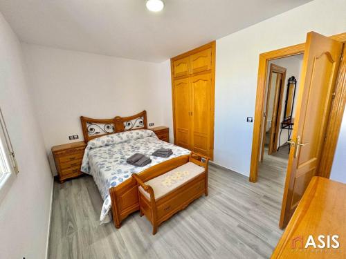 1 dormitorio con cama de madera y puerta de madera en Apartamento asis B, en Albuñán