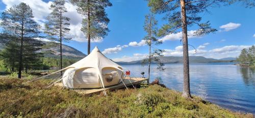 une tente blanche installée sur la rive d'un lac dans l'établissement Telemark Camping, à Hauggrend