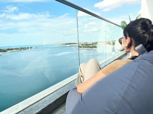 a woman sitting on a balcony looking out at the water at GuestReady - Viver com glamour em Palm Jumeirah in Dubai