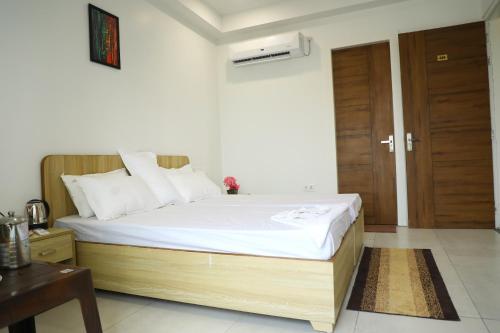 a bedroom with a bed with white sheets and a wooden door at Unio Mystica in Rishīkesh