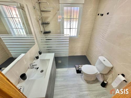 Un baño blanco con inodoro y lavabo. en Apartamaento Asis A, en Albuñán
