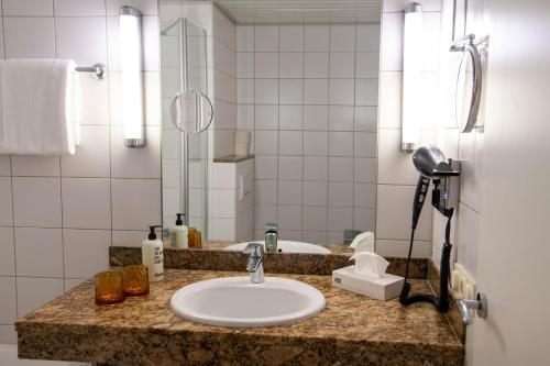 eine Badezimmertheke mit einem Waschbecken und einem Spiegel in der Unterkunft SleepBEEONE AIRPORTHOTEL FRANKFURT MÖRFELDEN in Mörfelden-Walldorf