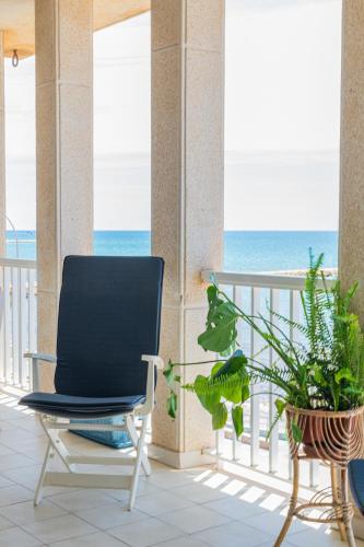 a chair on a balcony with the ocean in the background at Vistas Increíbles y Confort en 1ª Línea de Playa in Santa Pola