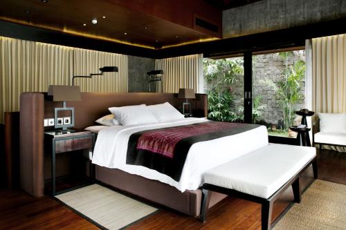 a bedroom with a large bed with a desk and a window at Sanctoo Suites & Villas in Gianyar