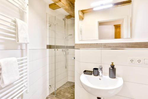 ein weißes Bad mit einem Waschbecken und einer Dusche in der Unterkunft Aparthotel an Sankt Marien in Stralsund