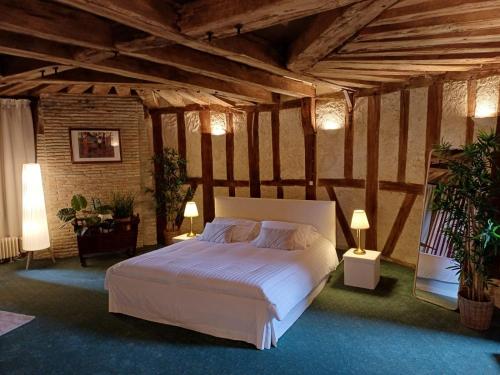 - une chambre avec un grand lit blanc et des plafonds en bois dans l'établissement Maison d hôtes du chateau de Bouesse, à Bouesse