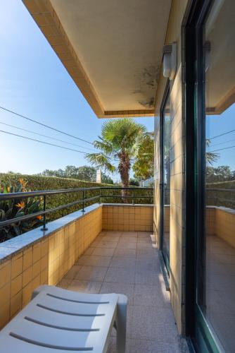 a white bench on a balcony with a palm tree at Retreat Hattie's Beach in Arcozelo