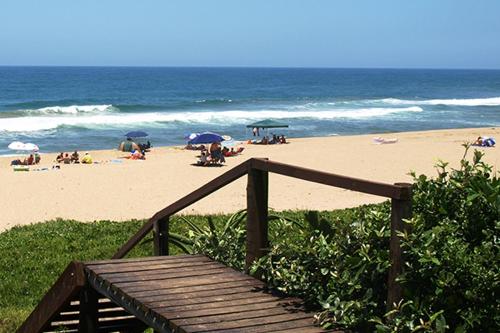 a beach with people sitting on the sand and umbrellas at Princes Grant 2 Bedroom Apartment in Blythedale