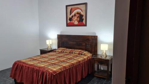 a bedroom with a bed and two night tables with lamps at Hospedaje El Cascabel in Sunampe