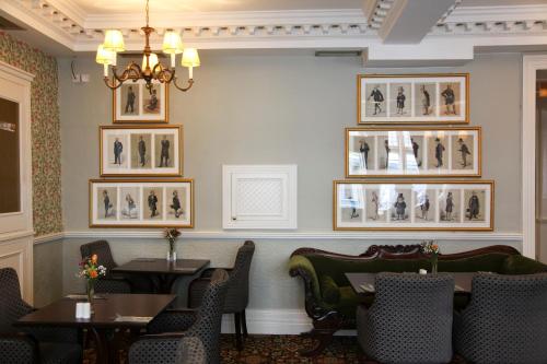 a dining room with tables and chairs and pictures on the wall at Club House Hotel Kilkenny in Kilkenny