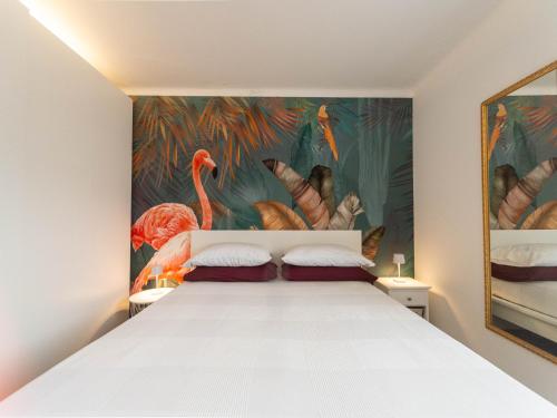 a bedroom with a white bed and a painting of flamingos at Elegante a due passi dal mare in Alassio