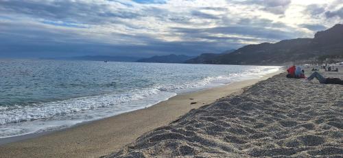 two people sitting on the beach near the water at Attico Morette, terrazzo - whazapp tre due 0 26 ott ott sei 2 quattro in Boissano