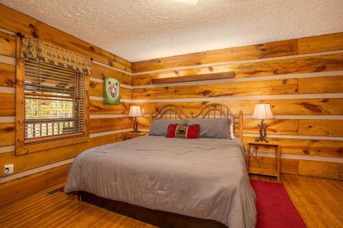a bedroom with a bed in a room with wooden walls at Cozy Bears Cabin by Eden Crest in Pigeon Forge