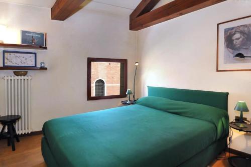 a bedroom with a green bed and a window at Ca' della Tana charming apartment in Biennale area in Venice