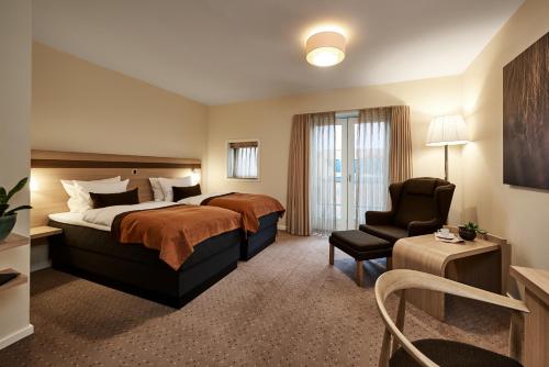um quarto de hotel com uma cama e uma cadeira em Montra Hotel Sabro Kro em Sabro