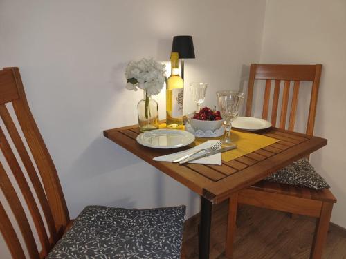 a wooden table with plates and glasses and flowers on it at Apartment Astoria in Krilo