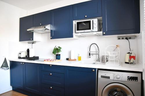 une cuisine avec des armoires bleues et un lave-linge dans l'établissement Vue Pyrénéenne Élégante avec 2 chambres, à Tarbes